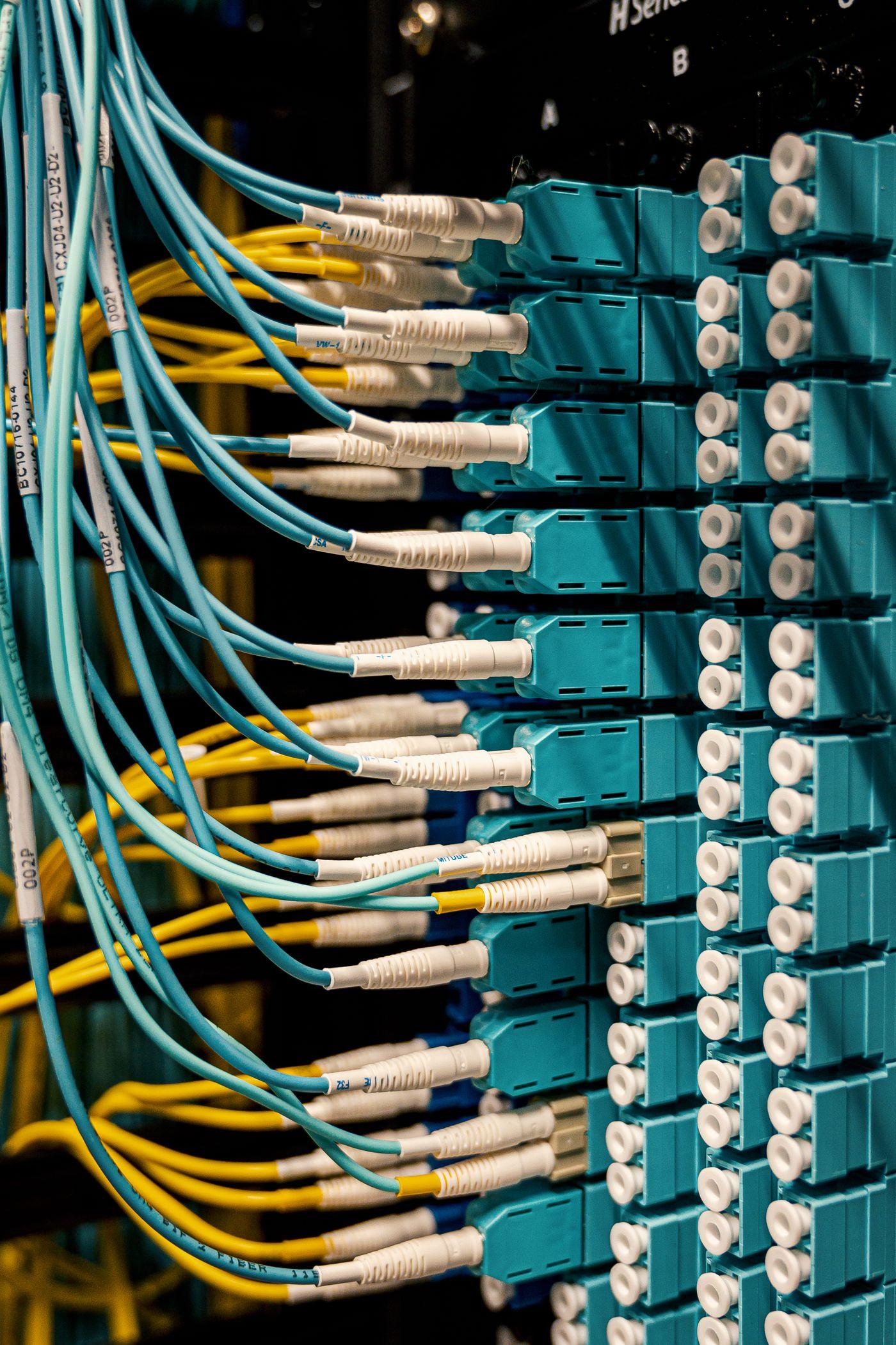 Painel de fibra óptica visto de perto, com cabos amarelos e azuis conectados em fileiras